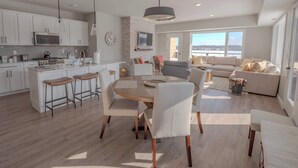 Una cucina moderna con mobili bianchi, un'isola centrale con sgabelli e un'area pranzo con un tavolo rotondo e sedie.