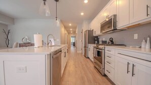 Una cucina moderna con mobili bianchi, elettrodomestici in acciaio inossidabile e pavimento in legno.