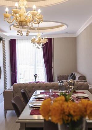 A dining area with a chandelier, a sofa, and a table set for a meal. - Sarot Thermal Palace Tatil Koyu - Halal Hotel (Mudurnu)