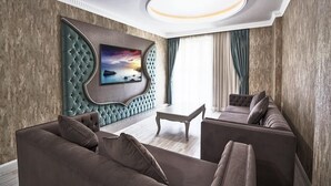 Un soggiorno moderno con un'ampia televisione a schermo piatto montata su una parete strutturata, un divano, un tavolino da caffè e un lampadario.