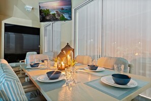 A dining area with a TV mounted on the wall, a fireplace, and a view of the ocean. - Last Minute Disney Getaway! Villa with Private Pool & Hot Tub. Book Now! #44 (Orlando)