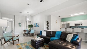 Un salon moderne avec un canapé en cuir foncé, une table basse et un coin repas comprenant une table et des chaises.