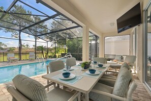 A covered outdoor area with a pool, seating, and a table set for dining. - Last Minute Disney Getaway! Villa with Private Pool & Hot Tub. Book Now! #44 (Orlando)