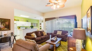Relax in this stylish living room with a sofa, coffee table, and dining area, featuring a kitchen with white cabinets and a backsplash.
