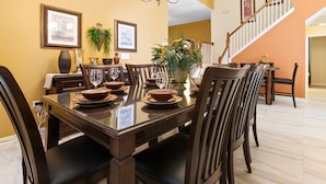 A dining area with a large table set for six, surrounded by chairs, with a staircase in the background. - Last Minute Disney Getaway! Private Pool, Hot Tub & Game Room. Book Now! #1388 (Orlando)