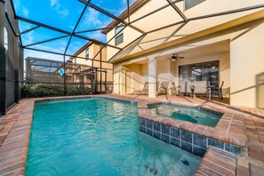 A swimming pool with a sunshade structure, a patio area with chairs, and a view of a building with a beige facade. - Last Minute Disney! Private Pool, Hot Tub, Game Room & Themed Bedrooms. Book Now! #15098 (Orlando)