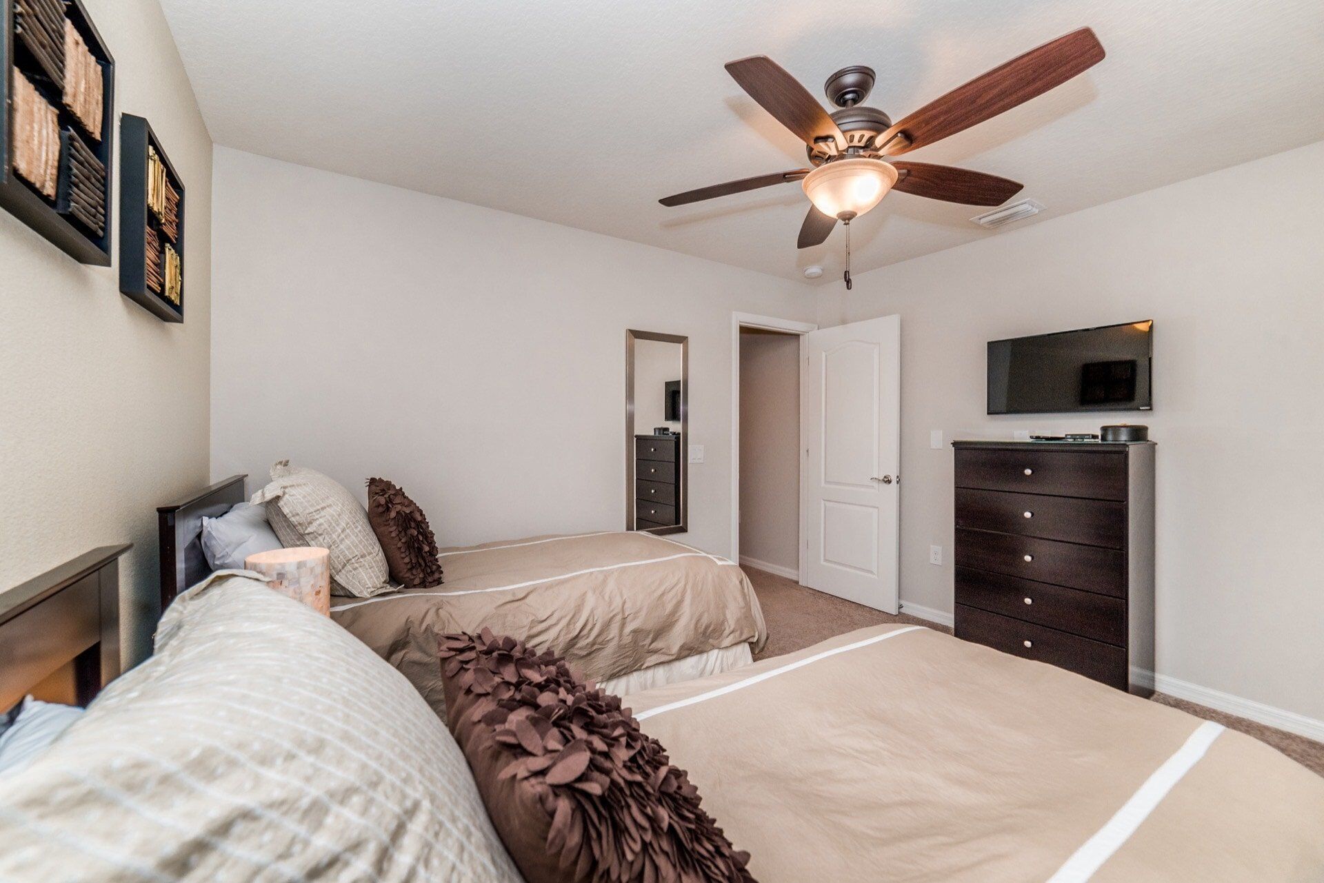 A bedroom with a bed, a dresser, a television, and a ceiling fan.