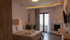 Habitación de hotel con cama, escritorio, silla, chimenea y balcón con cortinas.