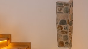 Una escalera de madera con iluminación empotrada, que lleva a una pared de piedra.