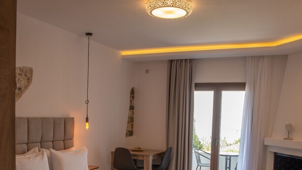 Habitación de hotel con una cama grande, un escritorio, una silla, una chimenea y un balcón con cortinas.
