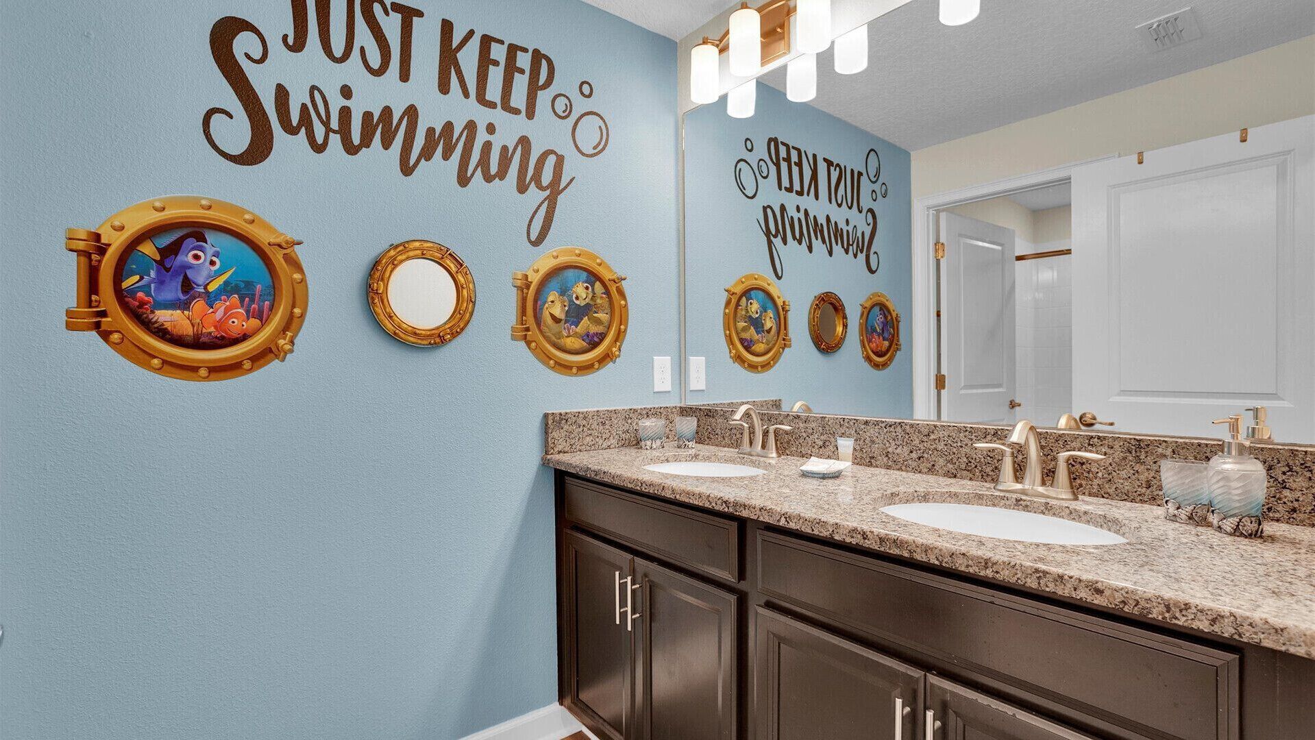 A bathroom with a blue wall, multiple mirrors, and decorative nautical-themed wall art.
