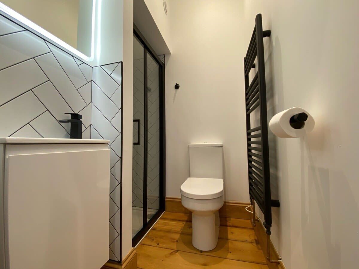 Une petite salle de bain avec des toilettes blanches, une douche en verre et un porte-serviettes.