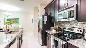 A modern kitchen with granite countertops, stainless steel appliances, and a backsplash. - Last Minute Disney Getaway! Townhouse with Private Pool. Book Now! #10656 (Orlando)