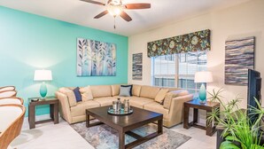 A living room with a sofa, coffee table, two side tables, a ceiling fan, and artwork on the walls. - Last Minute Disney Getaway! Townhouse with Private Pool. Book Now! #10656 (Orlando)