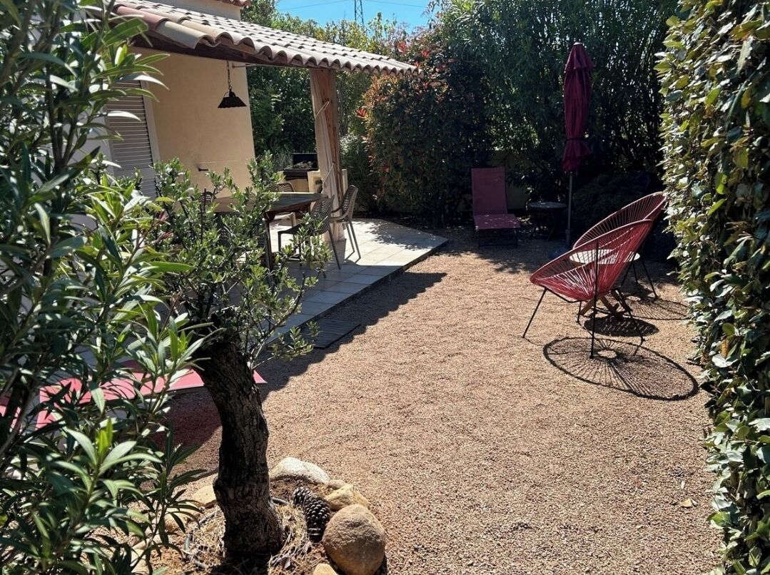 A patio area with a pergola, outdoor seating, and a gravel path.