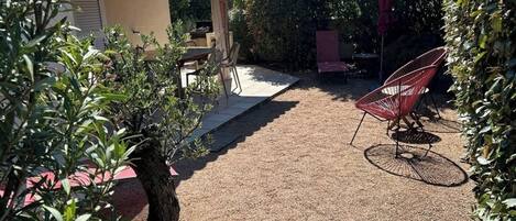 A patio area with a pergola, outdoor seating, and a gravel path.