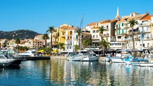 Un port de plaisance avec des bateaux amarrés, des bâtiments donnant sur le front de mer et des palmiers.