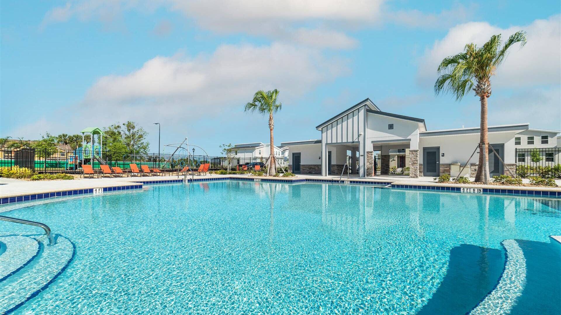 Une piscine d’un bleu éclatant, dotée de chaises longues, d  ’un espace abrité et d’un bâtiment à la façade en pierre.