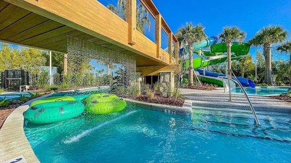 A pool area with a water slide, inflatable rings, and a wooden deck.