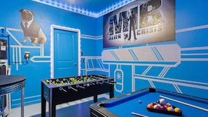 A room with a blue wall, a foosball table, a pool table, and a door. - Last Minute Disney! Private Pool, Game Room & Themed Bedrooms. Book Now! #43167 (Orlando)