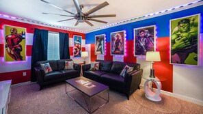 Relax in this stylish living room with a ceiling fan, two sofas, and a floor lamp, surrounded by framed posters and LED lighting.