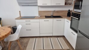 Une cuisine moderne avec des armoires blanches, un réfrigérateur en acier inoxydable, un four encastré et un plan de travail en bois.