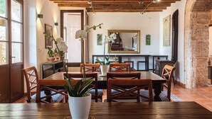 Een eetruimte met houten tafels en stoelen, potplanten en een grote spiegel aan de muur.