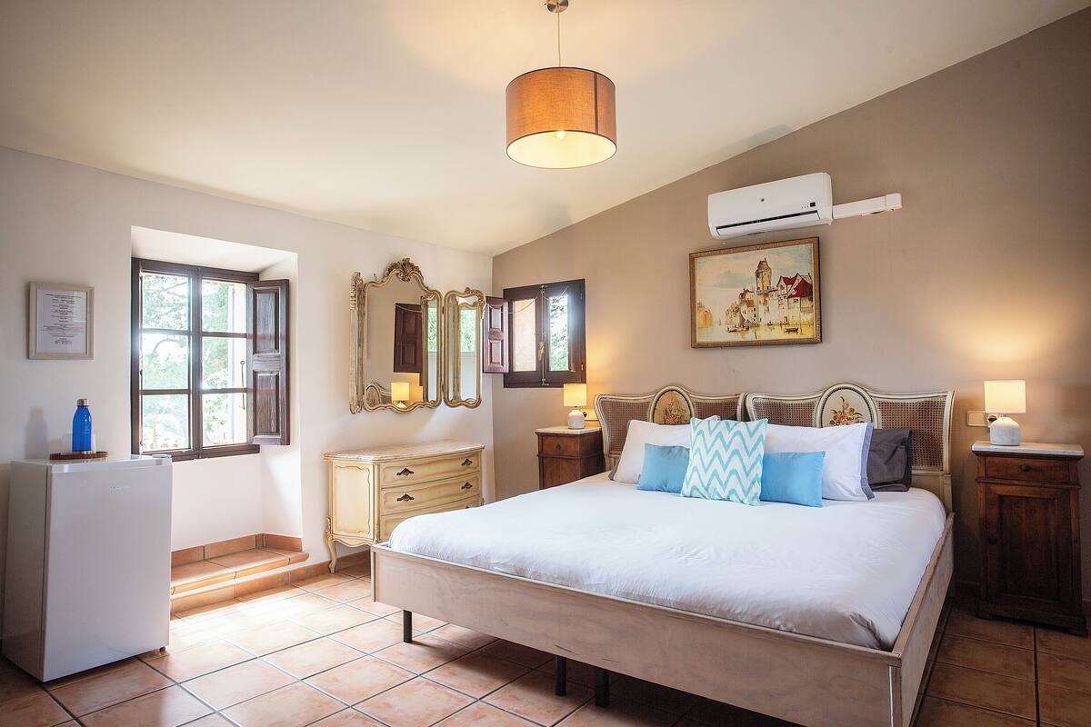 A bedroom with a large bed, a dresser, a mirror, and a window.