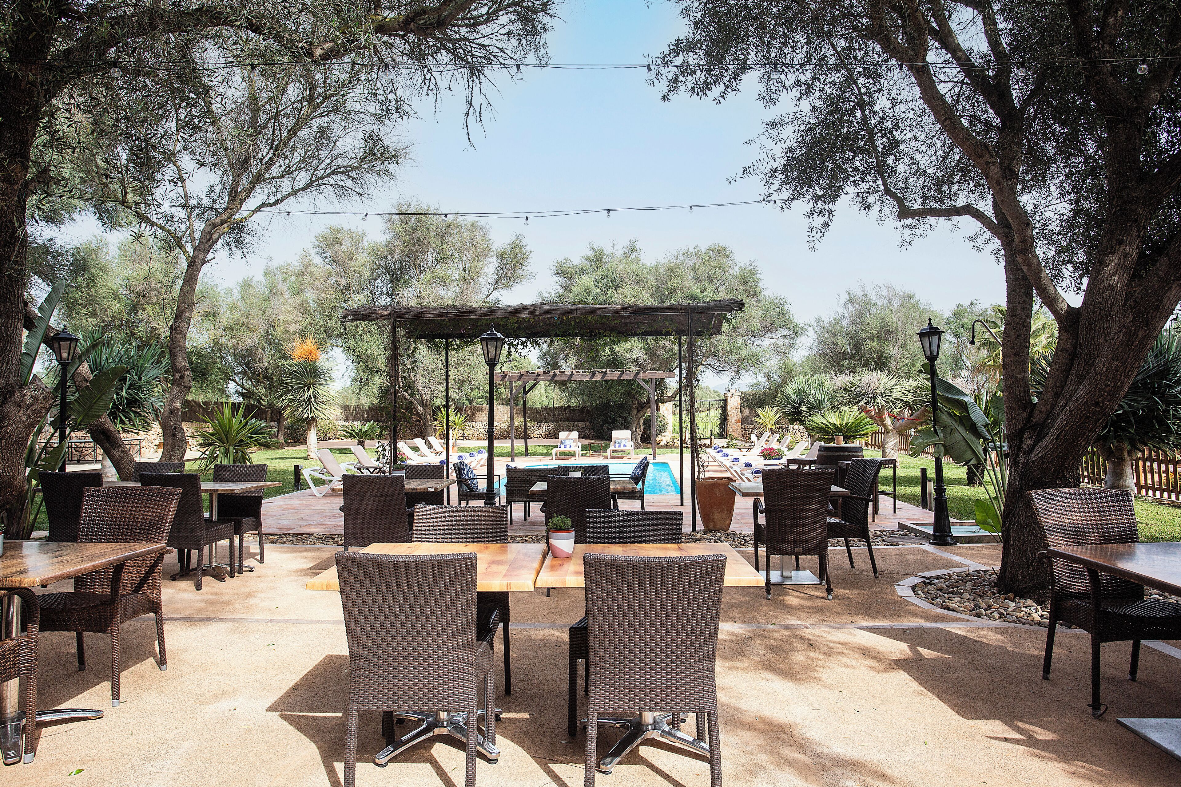 Un patio al aire libre con mobiliario de mimbre, una piscina y una pérgola.