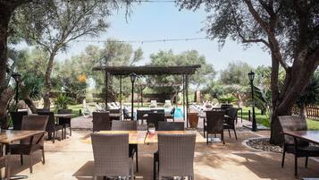 Un patio al aire libre con mobiliario de mimbre, una piscina y una pérgola.