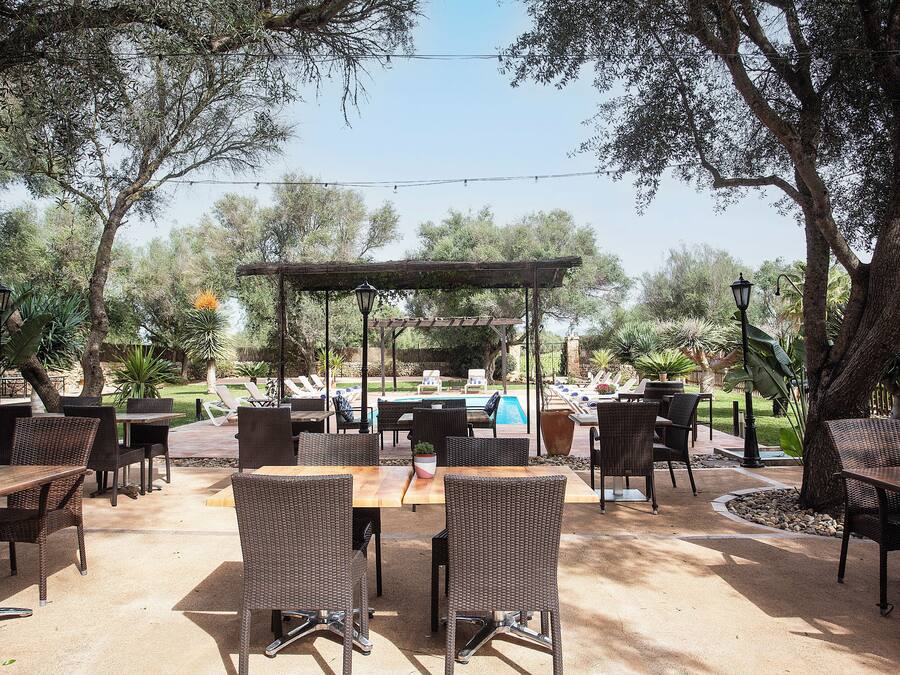 Un patio al aire libre con mobiliario de mimbre, una piscina y una pérgola.
