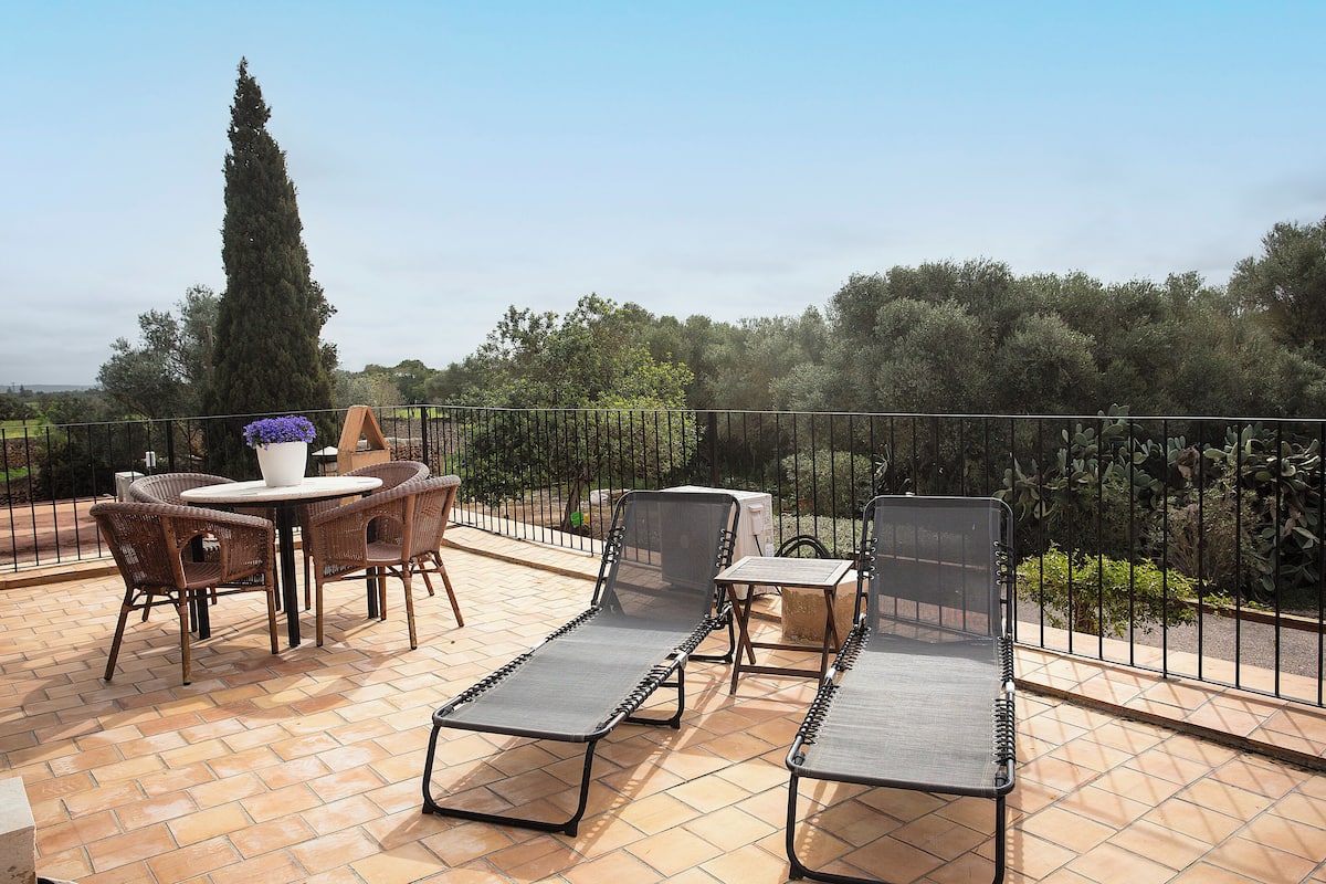 An outdoor patio with a round table, four wicker chairs, and two lounge chairs.
