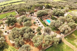 An aerial view of a property with a swimming pool, outdoor seating, and a garden area.