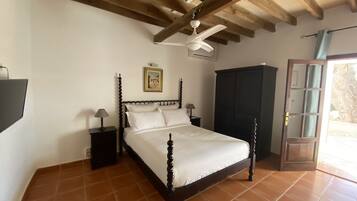 Un dormitorio con cama, mesita de noche, armario y ventilador de techo.