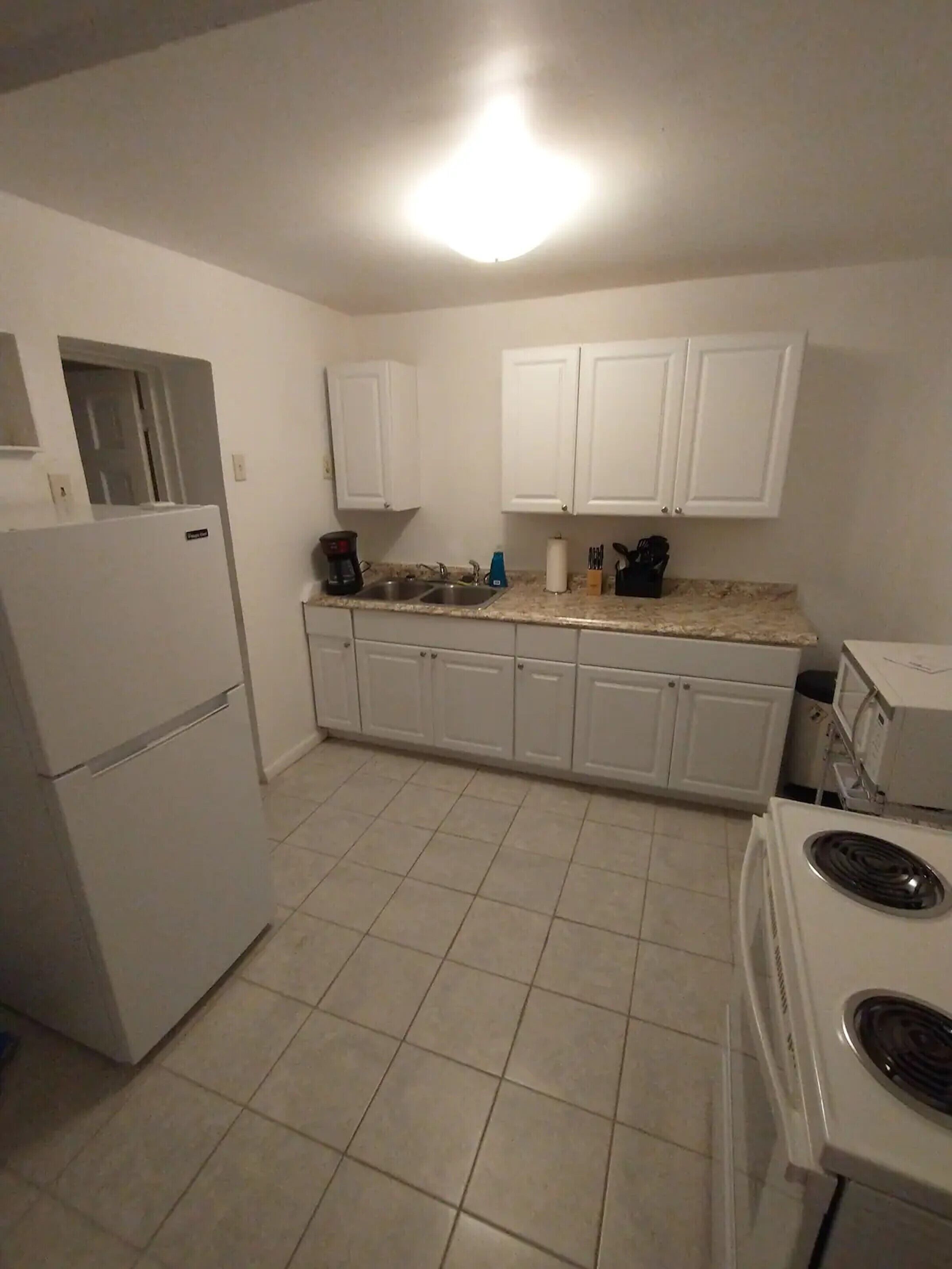 A kitchen with white cabinets, a refrigerator, a stove, and a microwave.