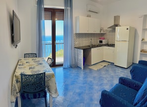 A compact living space with a dining area, kitchenette, and a balcony with a view.