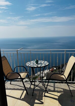 Un balcón con mesa y sillas, con vistas a la costa.