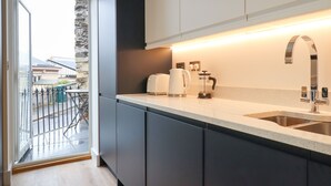 Una cocina moderna con armarios oscuros, una encimera blanca, una cafetera y un fregadero.