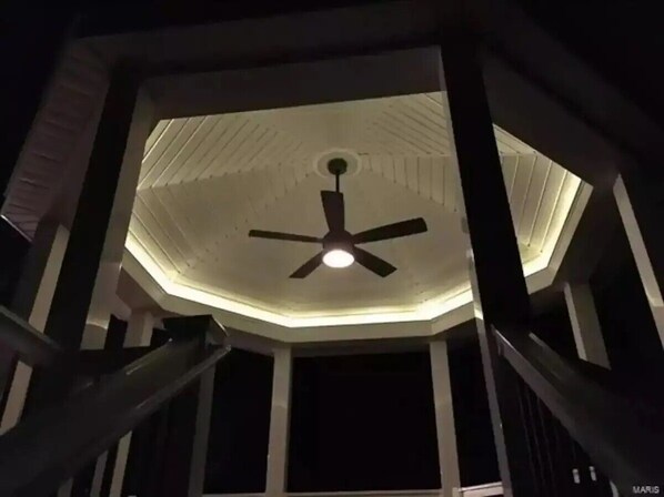 Un ventilador de techo en una habitación con un diseño geométrico en el techo.