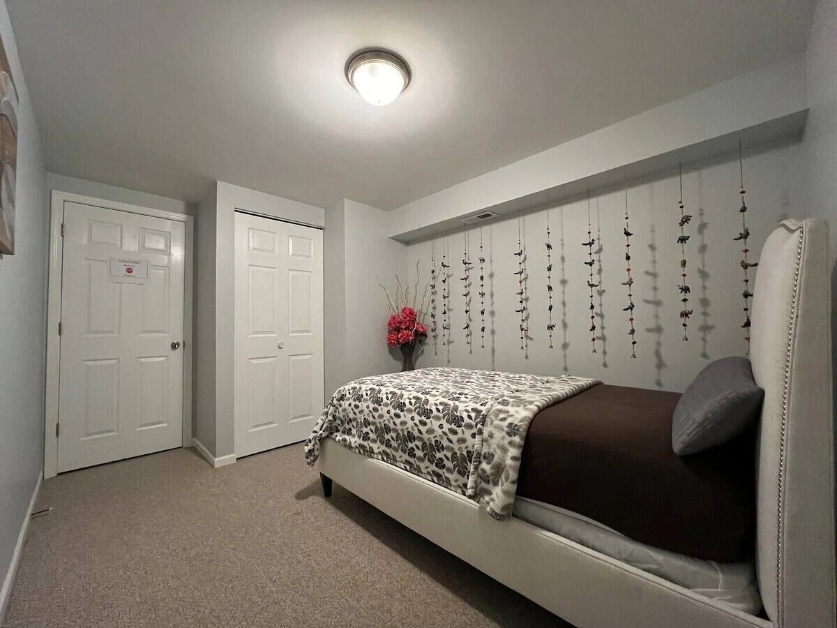 Une chambre à coucher avec un lit, une porte blanche et un mur orné de décorations suspendues.