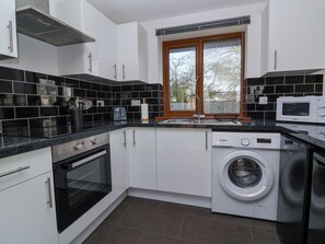 A compact kitchen with a washing machine, a microwave, and a toaster.