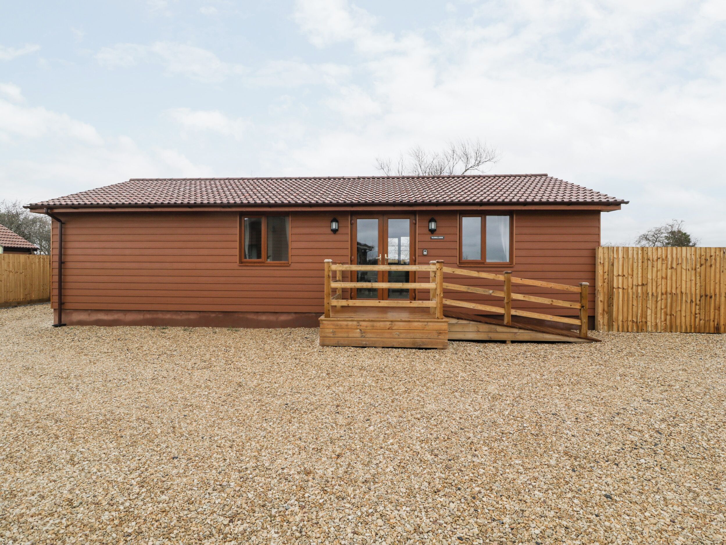 A wooden building with a tiled roof, a wooden gate, and a gravel driveway.