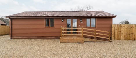 A wooden building with a tiled roof, a wooden gate, and a gravel driveway.