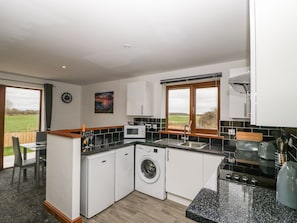 A compact kitchen with a washing machine, microwave, and sink.