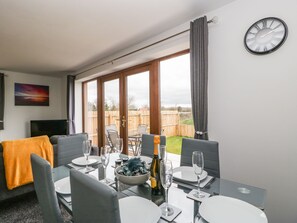 A dining area with a table set for two, a bottle of champagne, and a bowl of food.