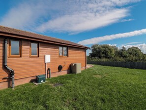 A wooden house with a tiled roof, a grassy yard, and a wooden fence.