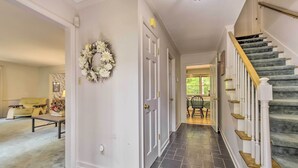 Un couloir avec un escalier, une porte décorée d’une guirlande, un canapé et une table basse.