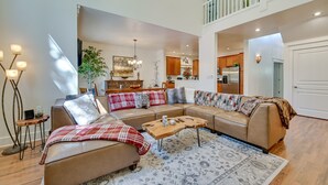 A spacious living room with a sectional sofa, a coffee table, and a rug. There is a staircase leading to an upper level. - Flagstaff Hideaway: Private Hot Tub, 4 Mi to Dtwn! (Flagstaff)