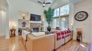 A spacious living room with a fireplace, a large clock, and a ceiling fan. - Flagstaff Hideaway: Private Hot Tub, 4 Mi to Dtwn! (Flagstaff)