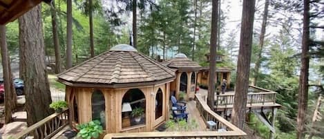 Eine Holzdar Terrasse mit Gazebos, umgeben von hohen Bäumen.
